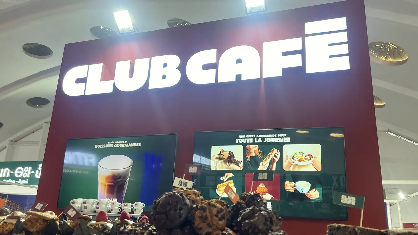 Enseigne lumineuse Club Café et deux écrans sur le mur de marque